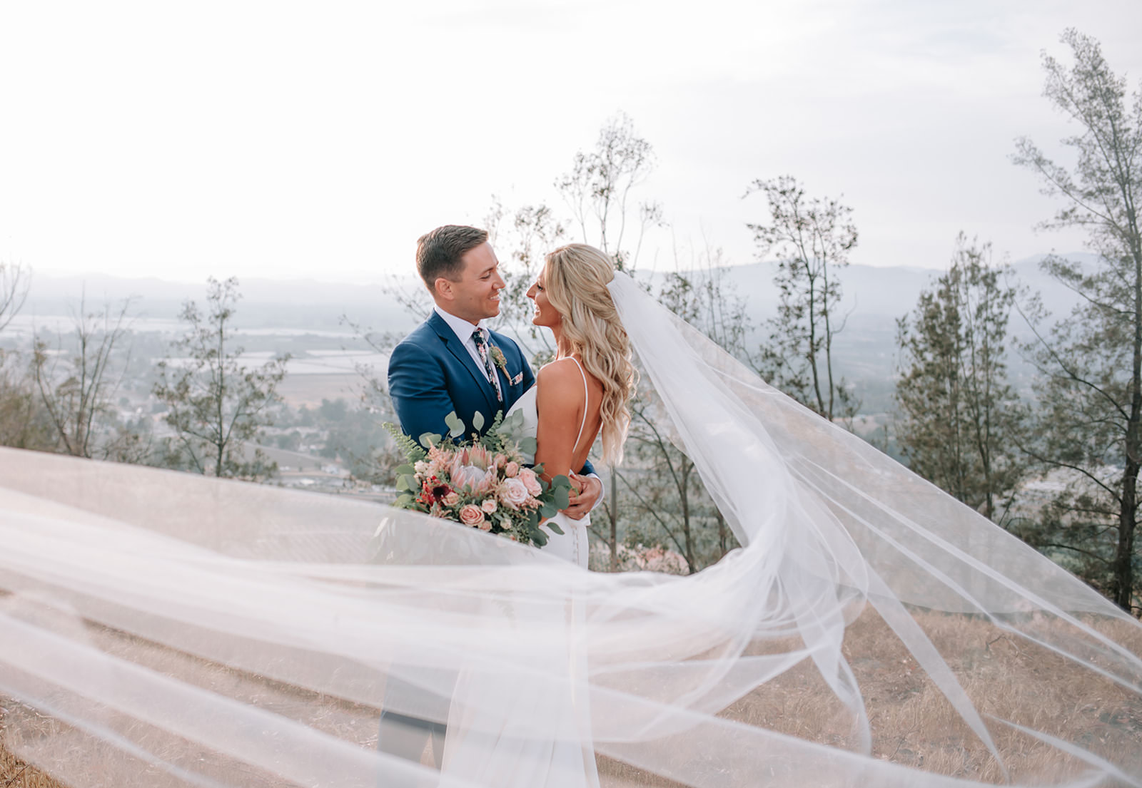 California backyard wedding couple kissing with mountains in the background with veil floating around