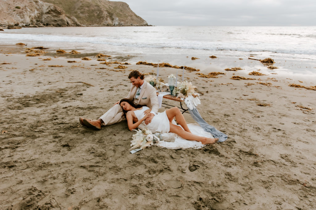 Bride laying in grooms lap on a Catalina Island Beach