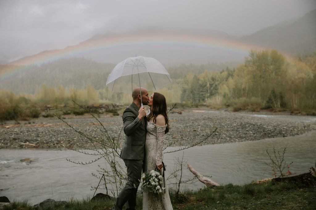 Elopement couple under a clear umbrella in Washington by a cabin