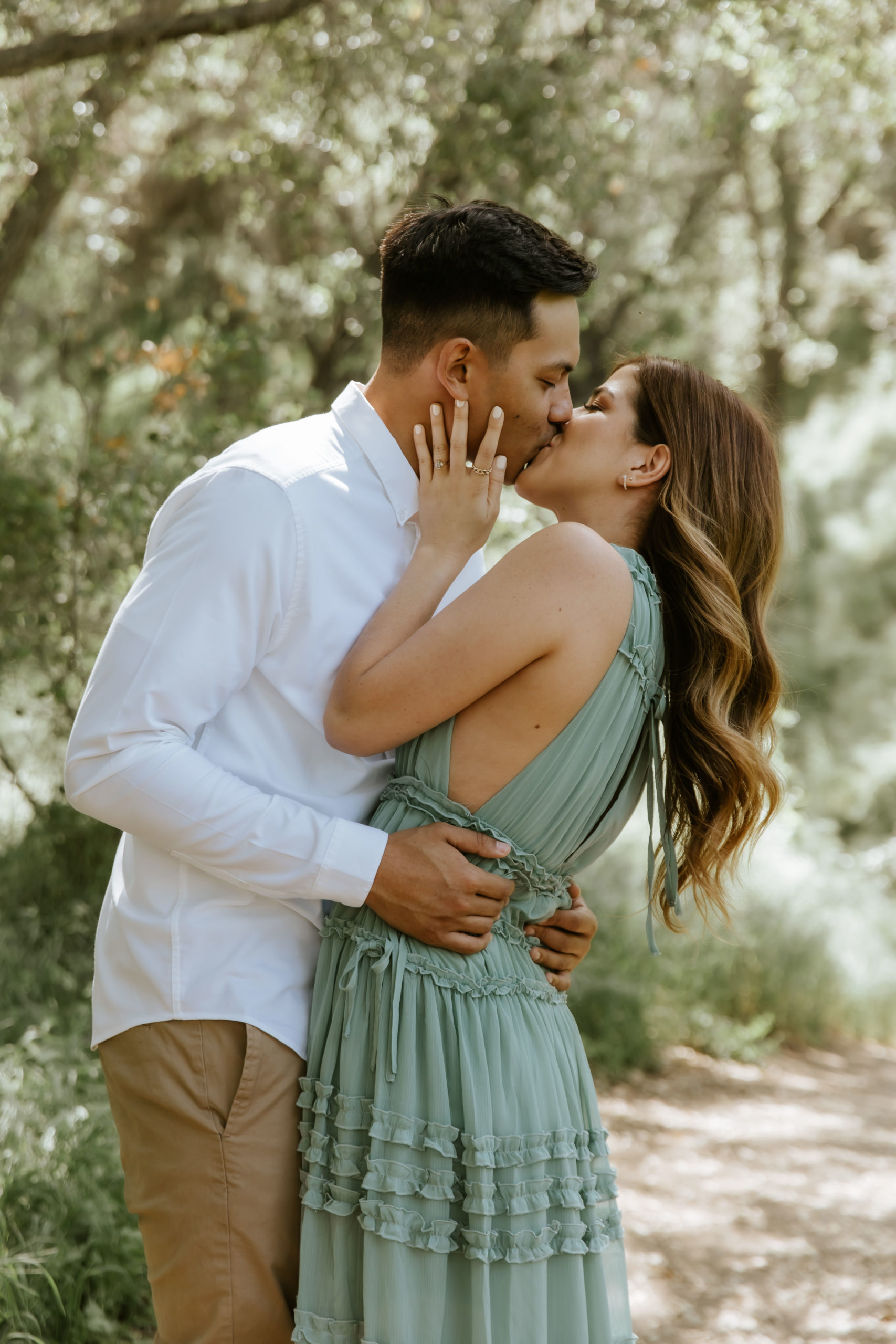 engaged couple kissing in the forest during their engagement photoshoot