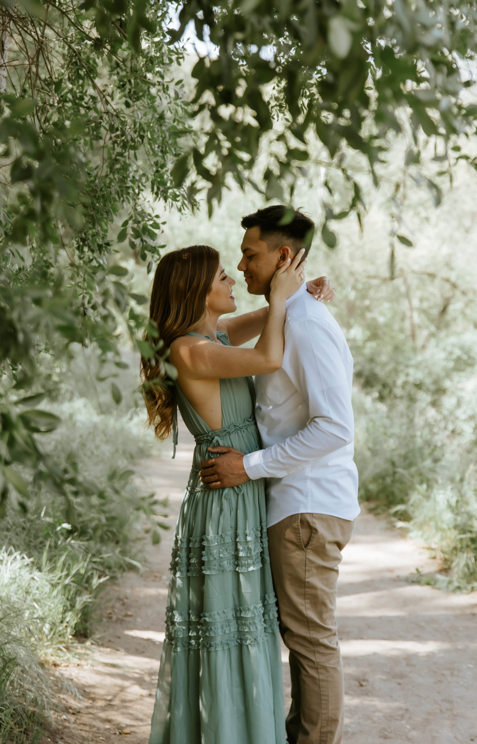 couple sharing an intimate moment under some trees during their engagement photos