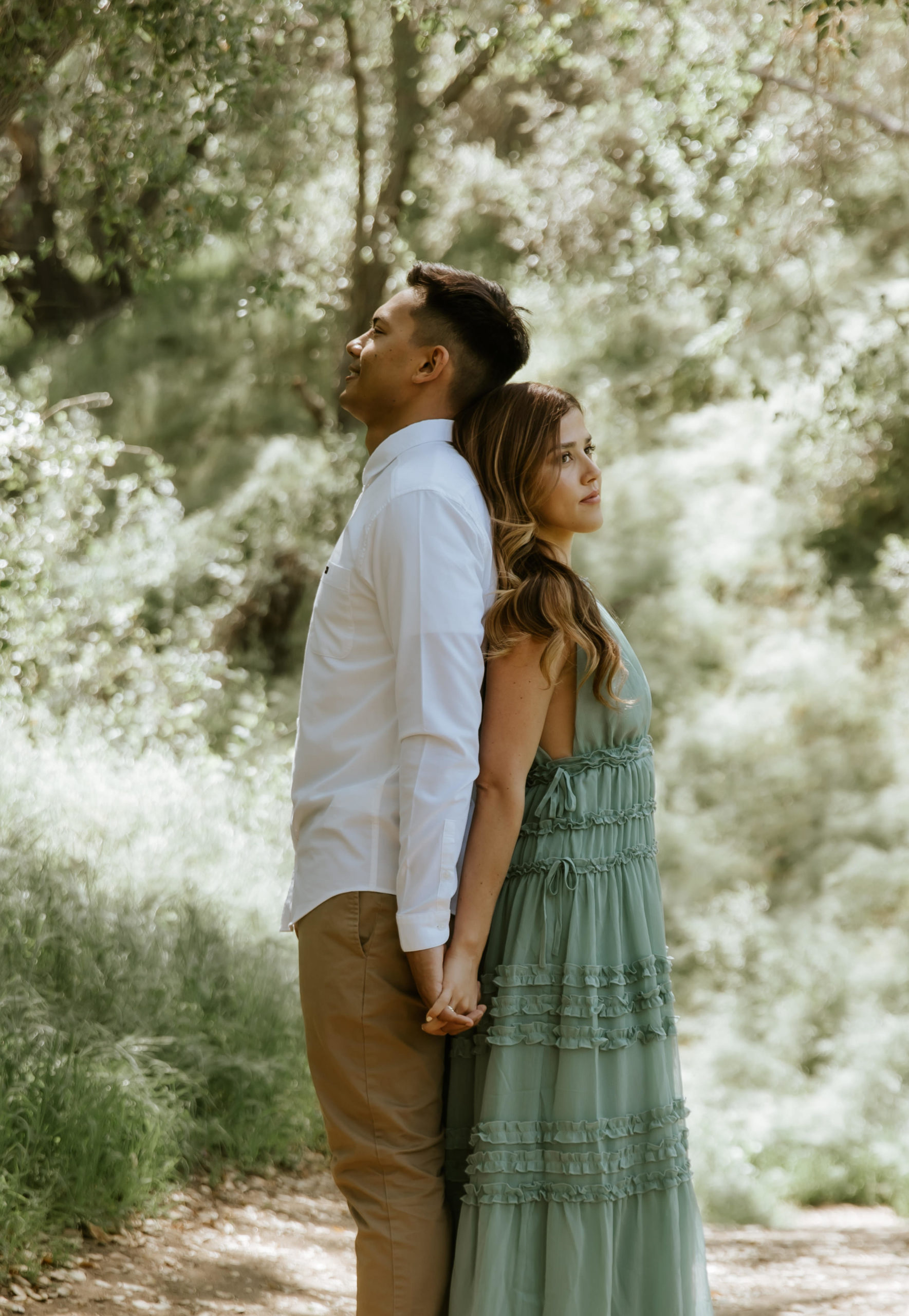 couple standing back to back in the forest during their engagement photos