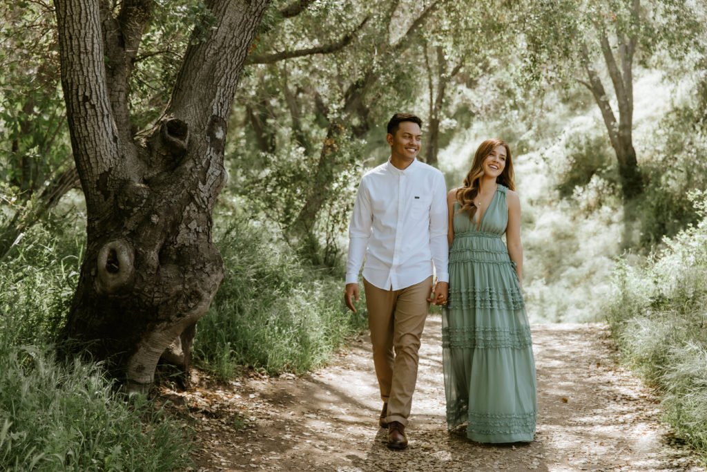 couple walking through forest during engagement photo session