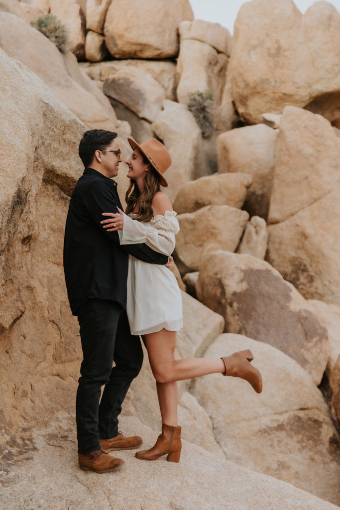 cute couple facing eachother with her leg popped up during engagement session