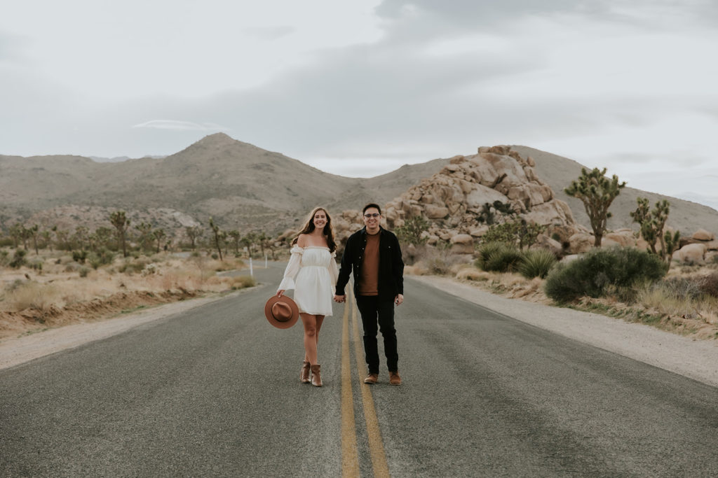 couple walking down road holding hands in Joshua Tree