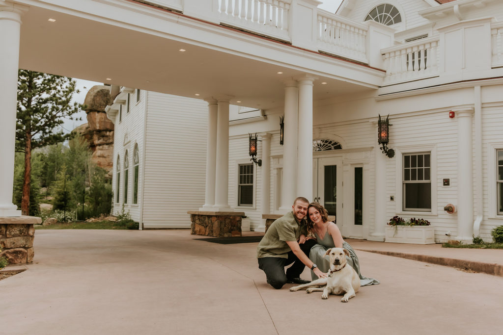 couple outside of the stanley hotel in estes park colorado with their dog