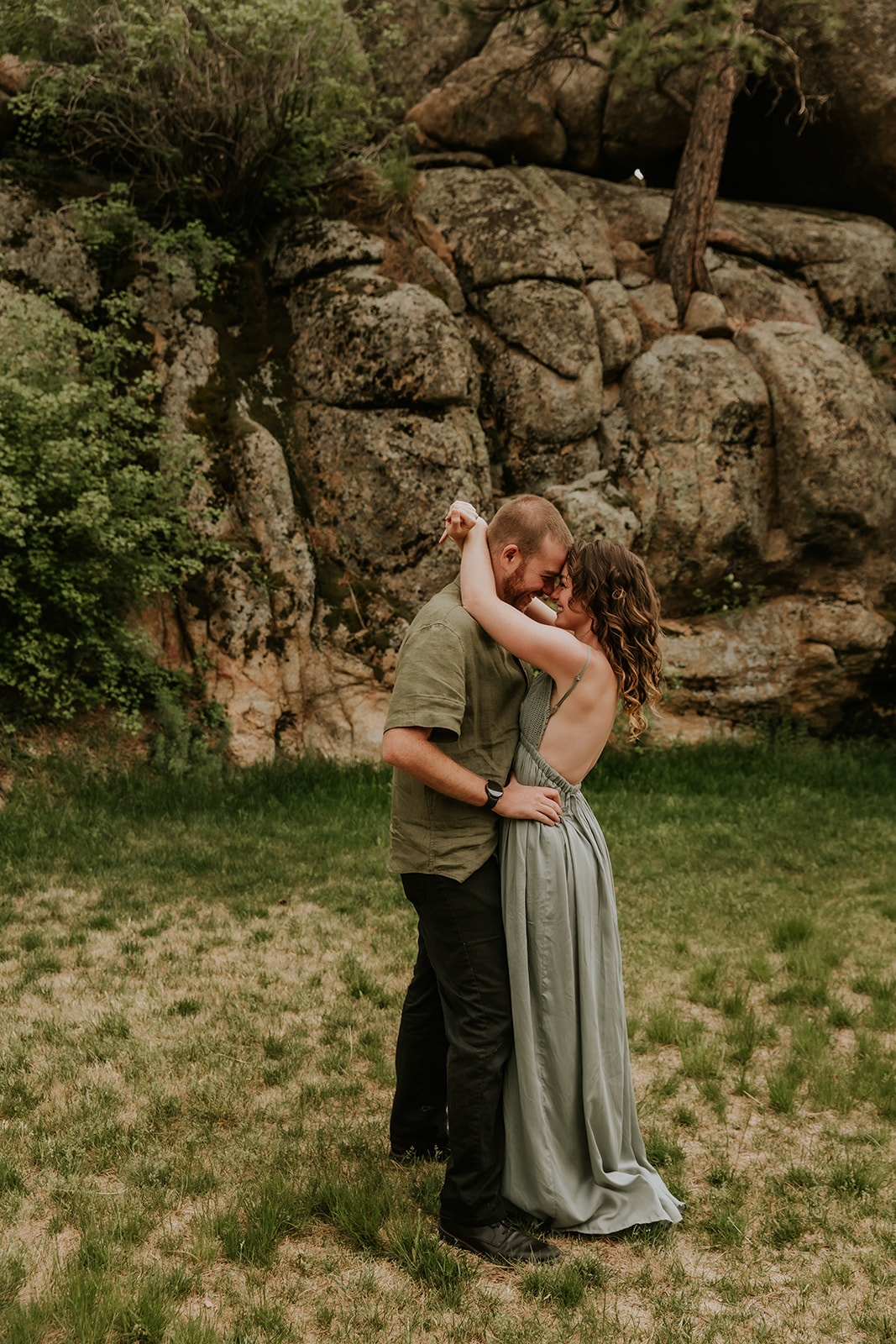 couple embraced in front of a rock at the stanley hotel in estes park colorado