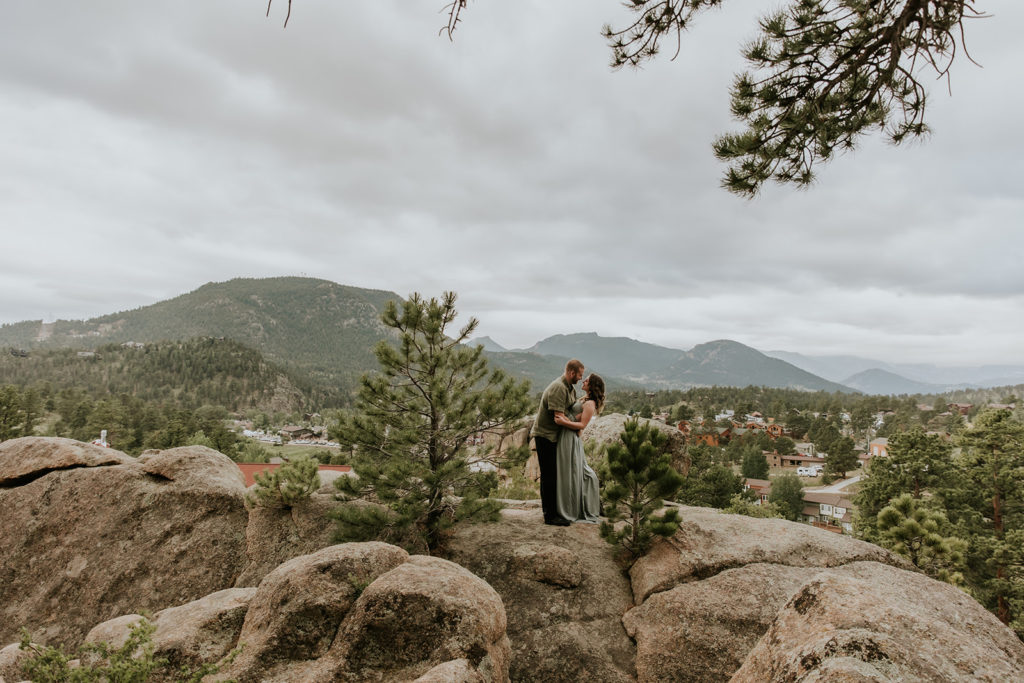 couple standing on top of rock with the rocky mountains behind them