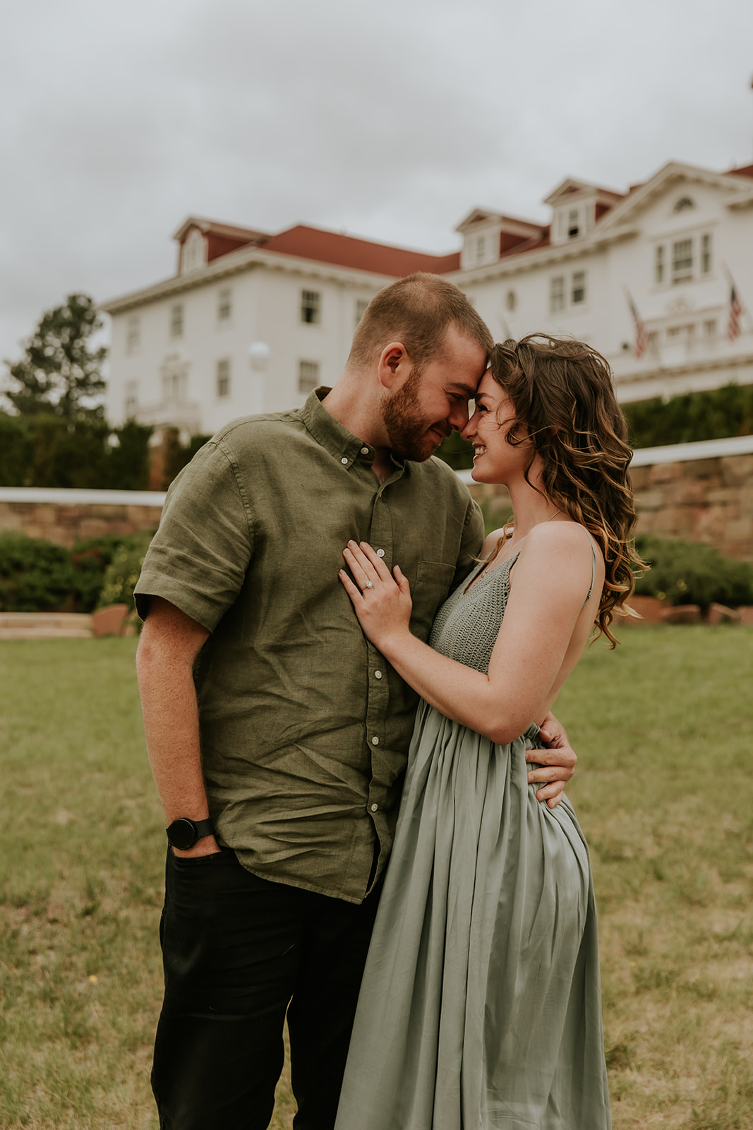 Couple touching foreheads together in front of the stanley hotel in estes park colorado