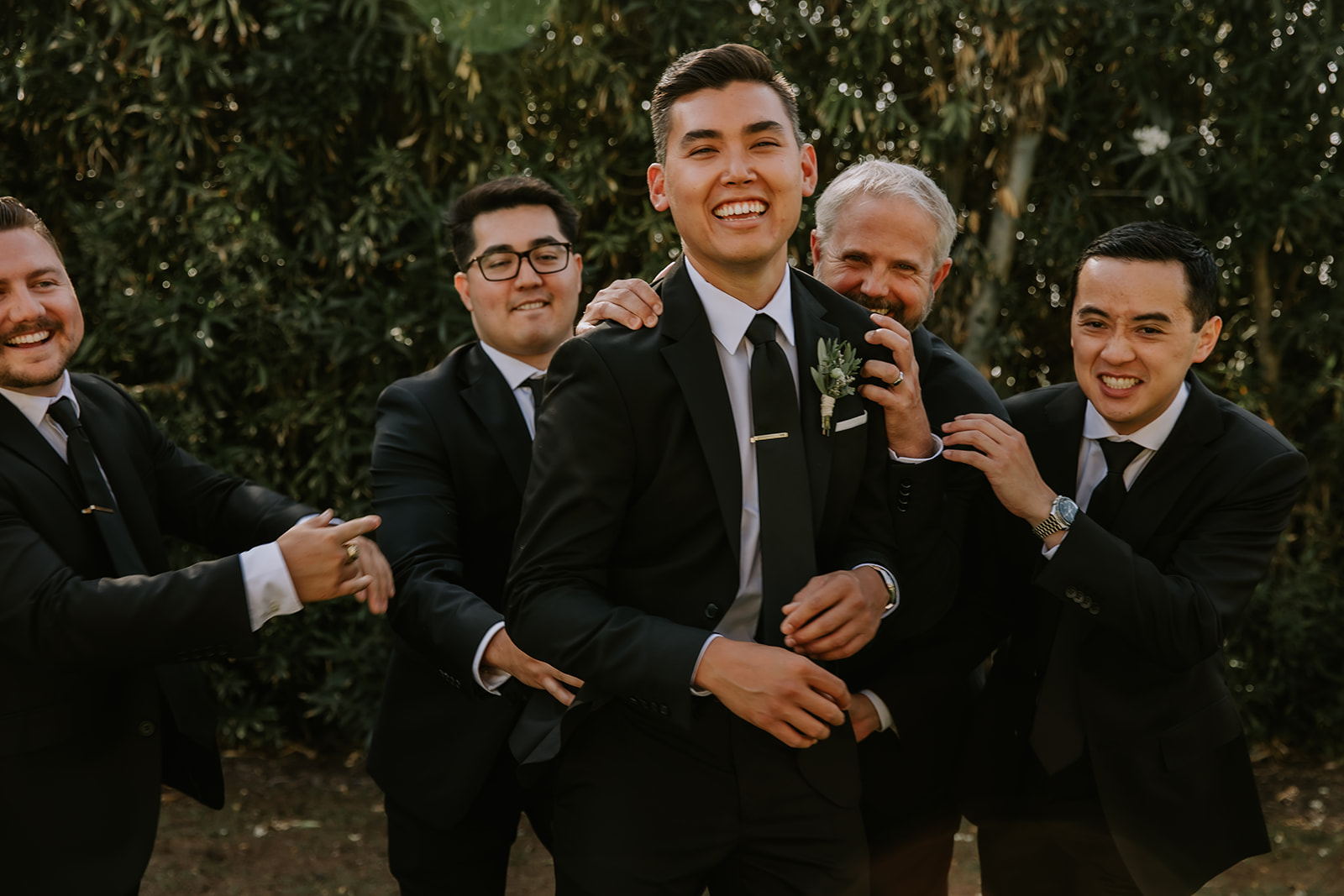groom being pushed around by his groomsmen having fun before the ceremony