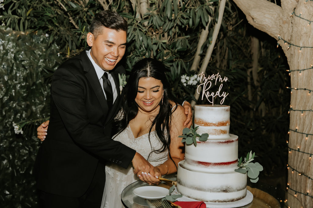 bride and groom cutting their wedding cake while smiling