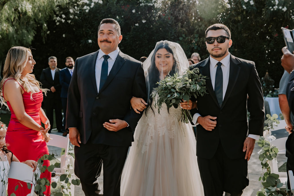 Father and brother of the bride walking her down the aisle at The Orchard by Wedgewood weddings in Menifee California
