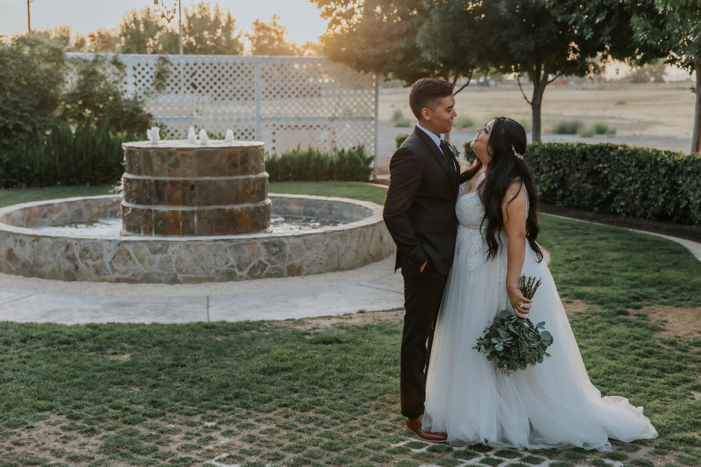 sunset photo of bride and groom near a fountain on the grounds of the wedding venue The Orchard by Wedgewood Weddings in Menifee California