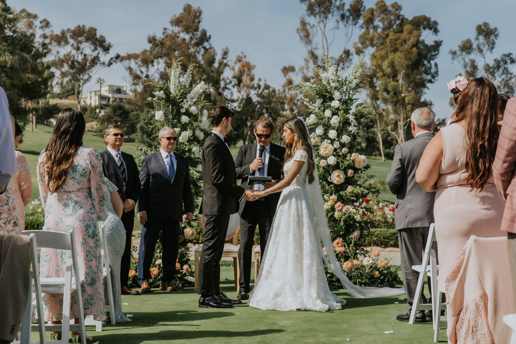 Bride and Groom holding hands during their ceremony at the Marbella Country Club in San Juan Capistrano