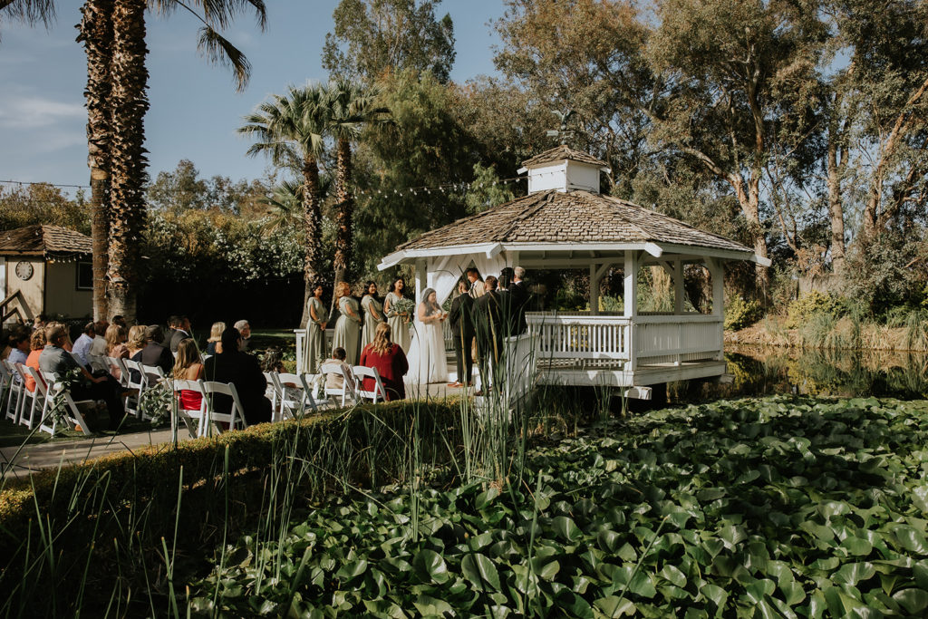 Couple Standing at the Gazebo on the Lily Pad Lake at The Orchard Wedding Venue in Menifee California