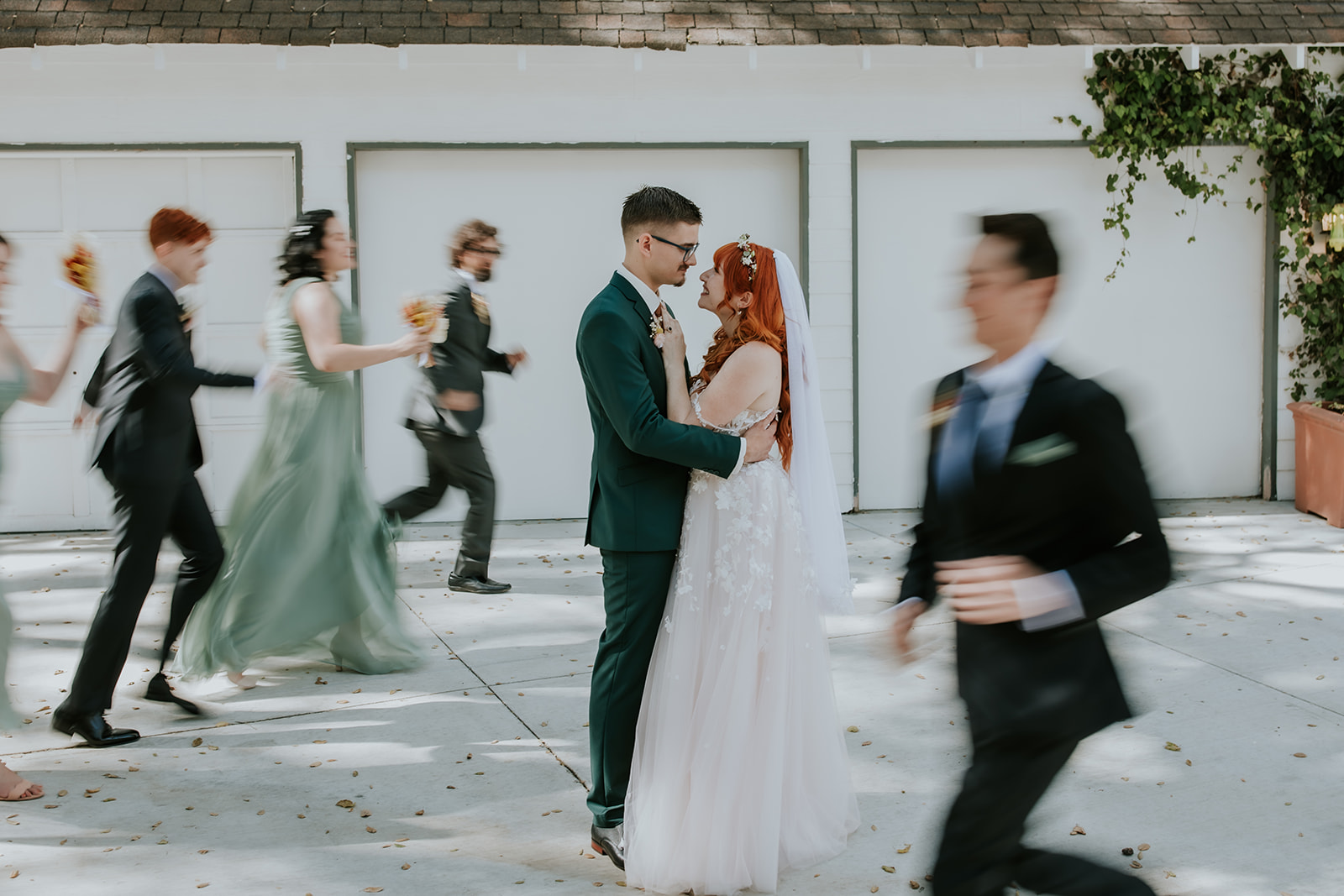 bride and groom facing each other hugging and smiling as their bridal party runs around them for a blurred effect