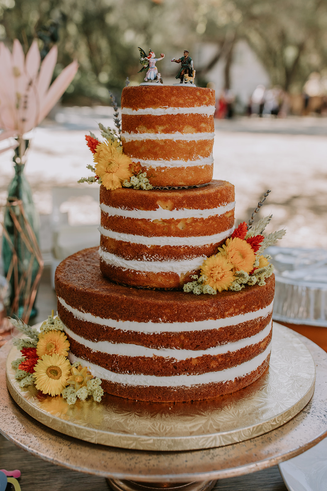 70s themed wedding cake with warm colored flowers placed on it