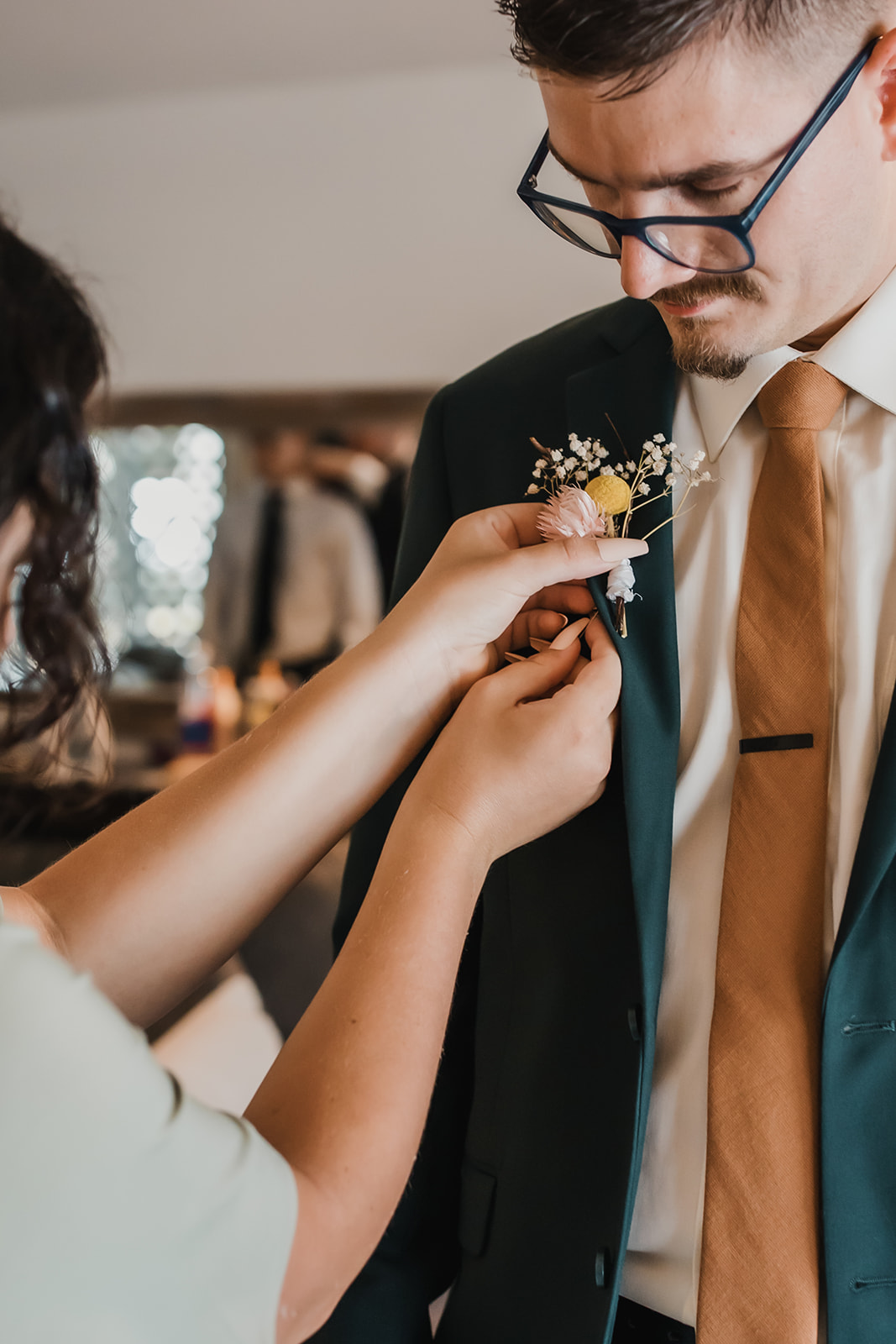 maid of honor pinning the grooms boutonniere on him