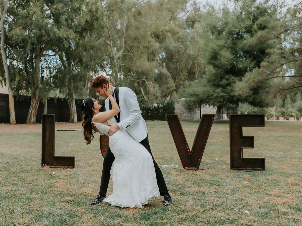 Groom dipping the bride in front a huge LOVE sign at the Blomgren Ranch