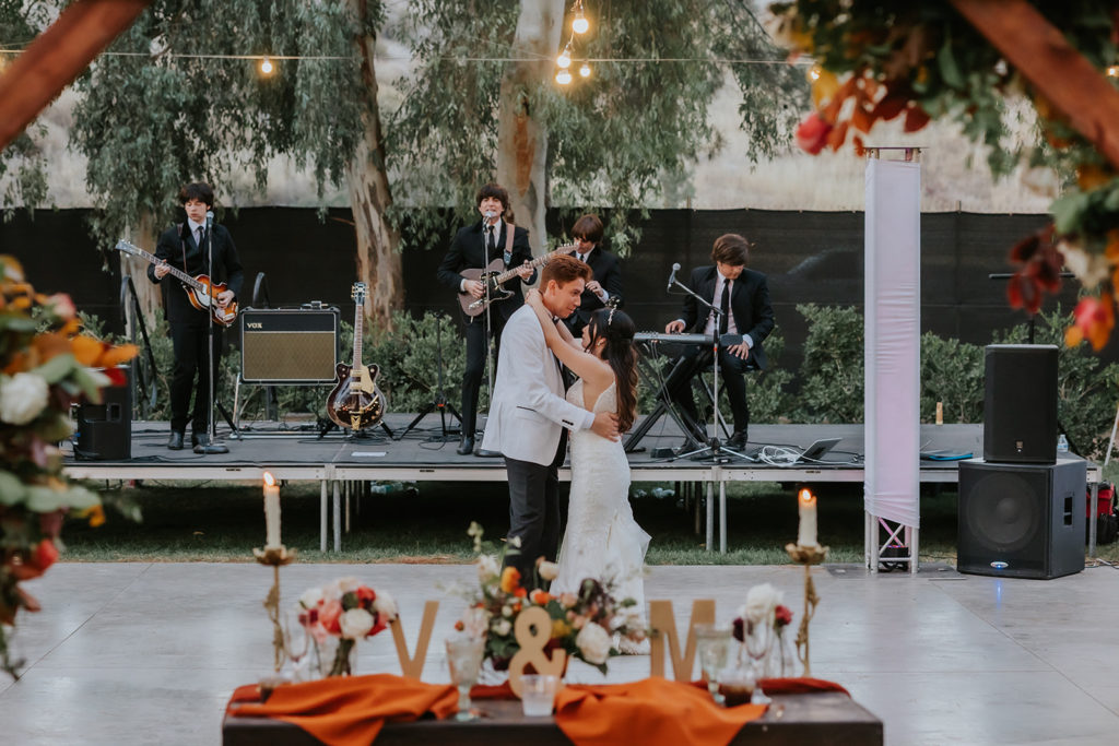 Bride and groom sharing their first dance to a beatles cover band at their 70s themed wedding