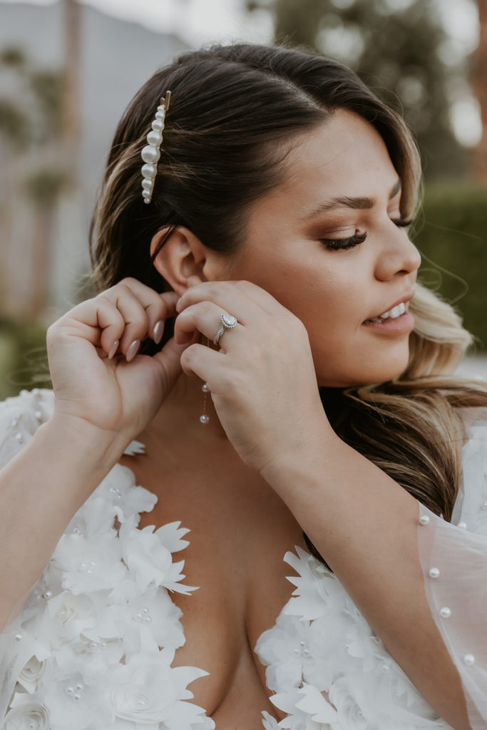 fiancee adjusting her earring during her engagement photos in palm springs