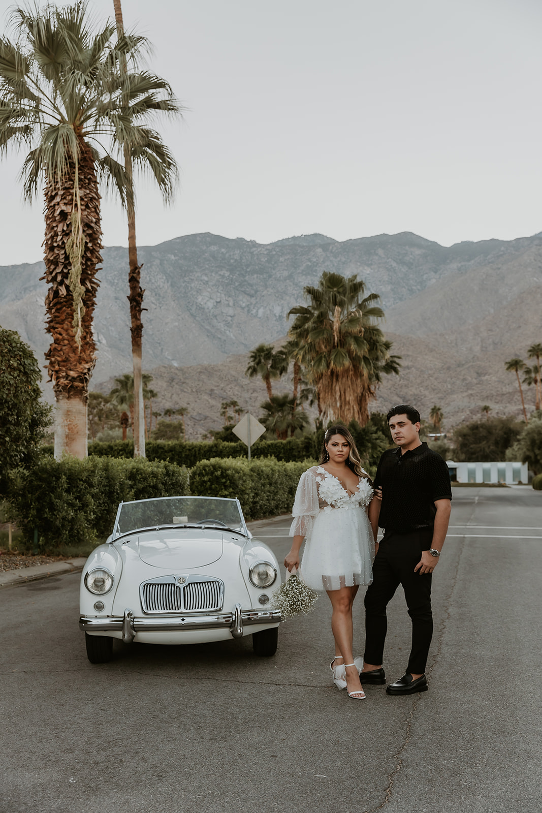 newly engaged couple standing outside of a classic car looking at the camera in Indian Canyon during their engagement session 