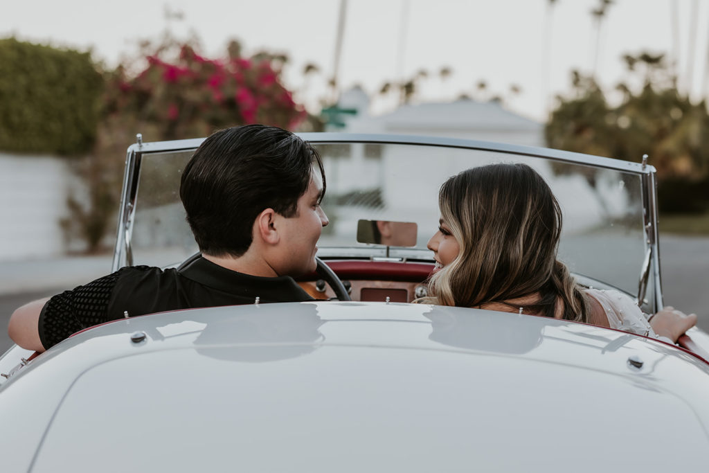 newly engaged couple sitting in a classic car driving away together during their engagement session
